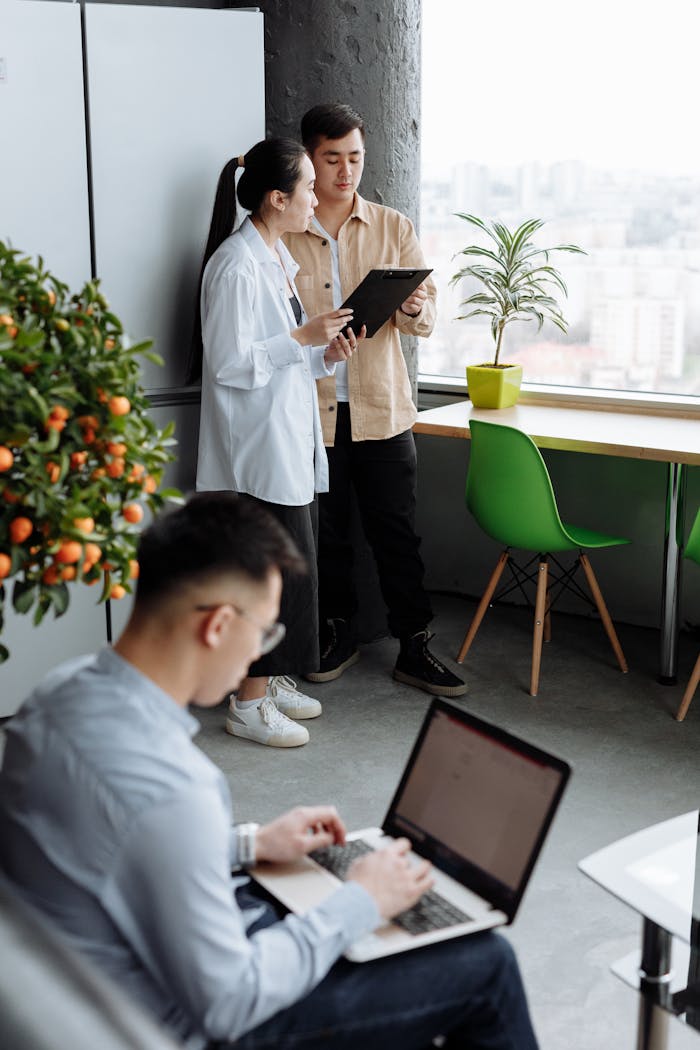 Team engaging in discussion and work in a modern office space with laptops and tablets.